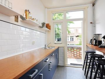 Galley kitchen with navy units, an oak worktop and a glazed door to the terrace