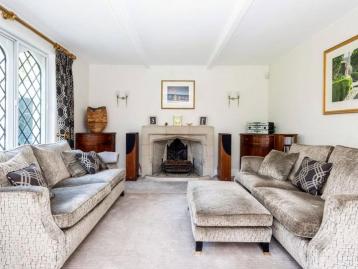 Sitting room with two sofas drawn up to an open fireplace beside a leaded window
